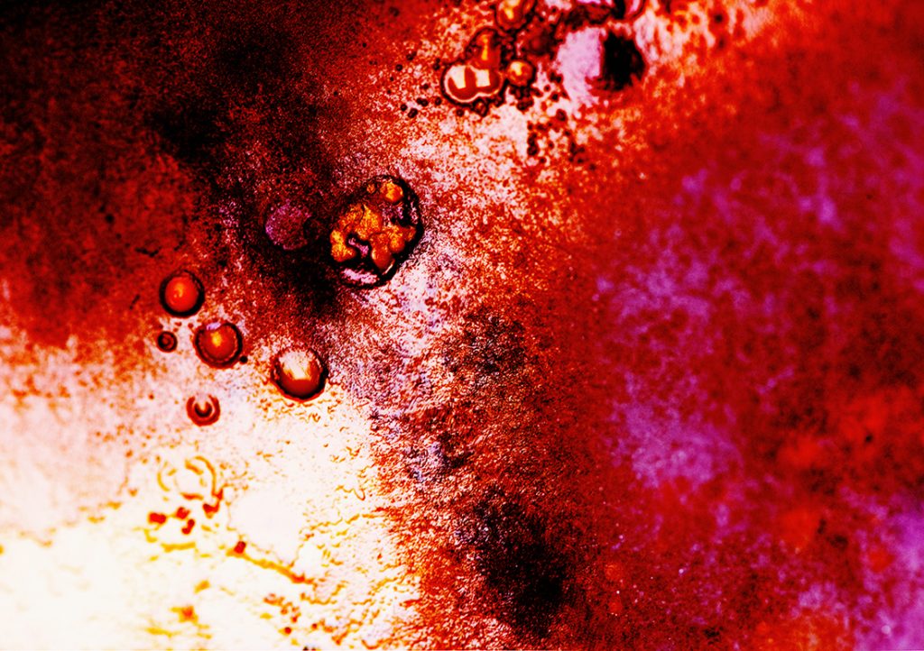The image is mostly taken up by large orange-red, pink, and yellow color splotches. In some areas, it looks like there are water droplets. 