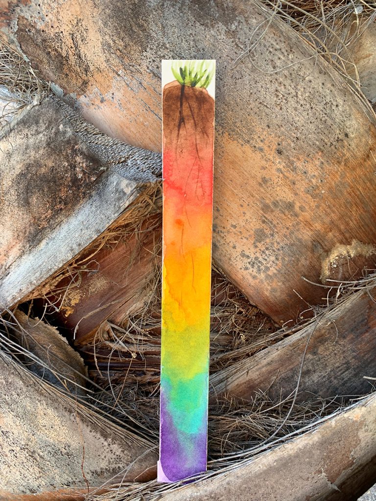 Thin painting of a small green plant on top with its roots in the soil. Beneath the brown soil is a rainbow gradient. Painting is sitting on thick trunk of a palm tree.