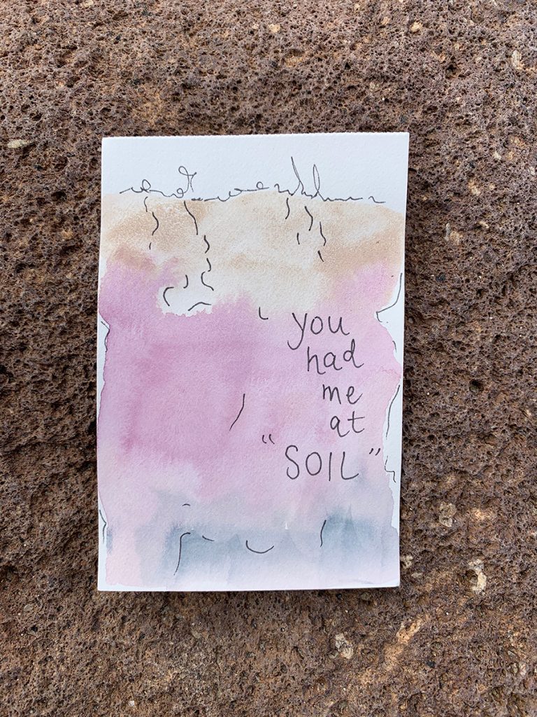 Simple soil profile with a gradient of light brown on top, pink in the center, and blue/grey at the bottom. The pink has "you had me at soil" written on top. The painting is resting on the dirt. 