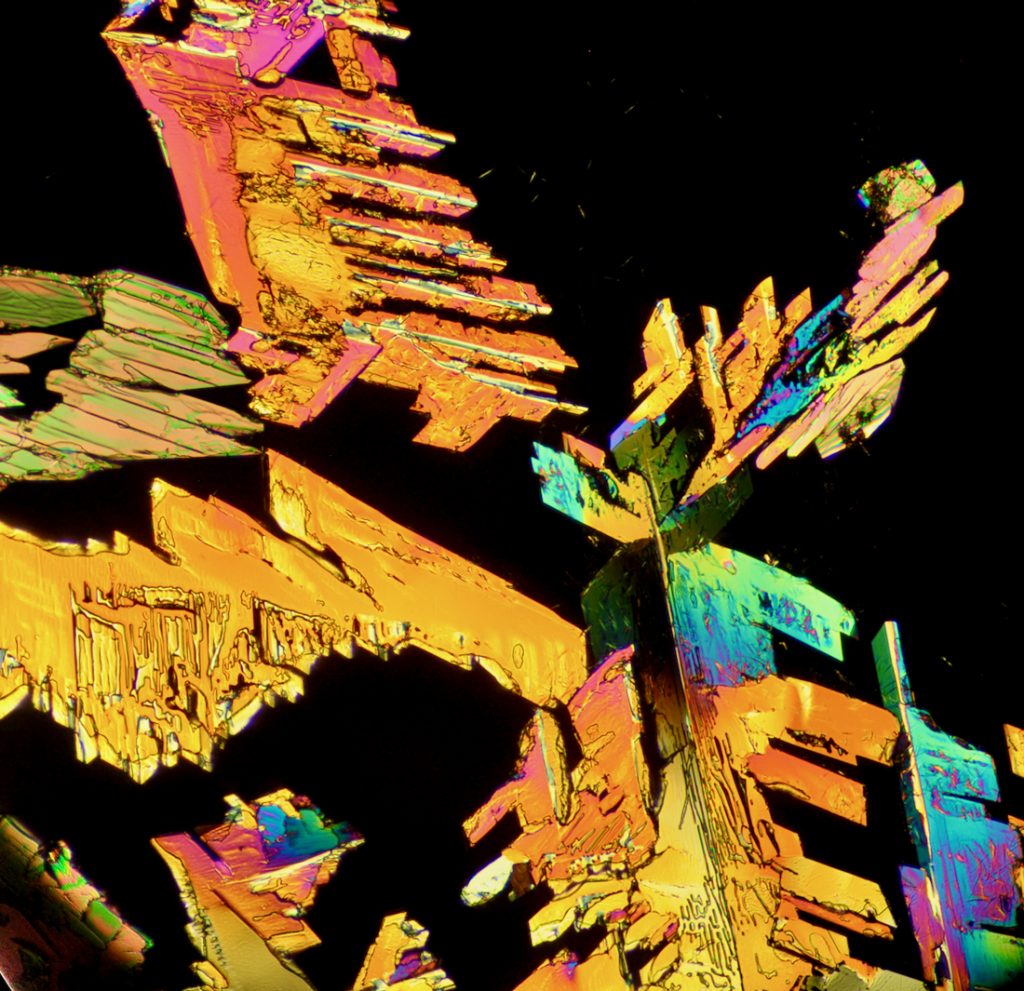 Jagged orange/iridescent crystal structures on a black background.