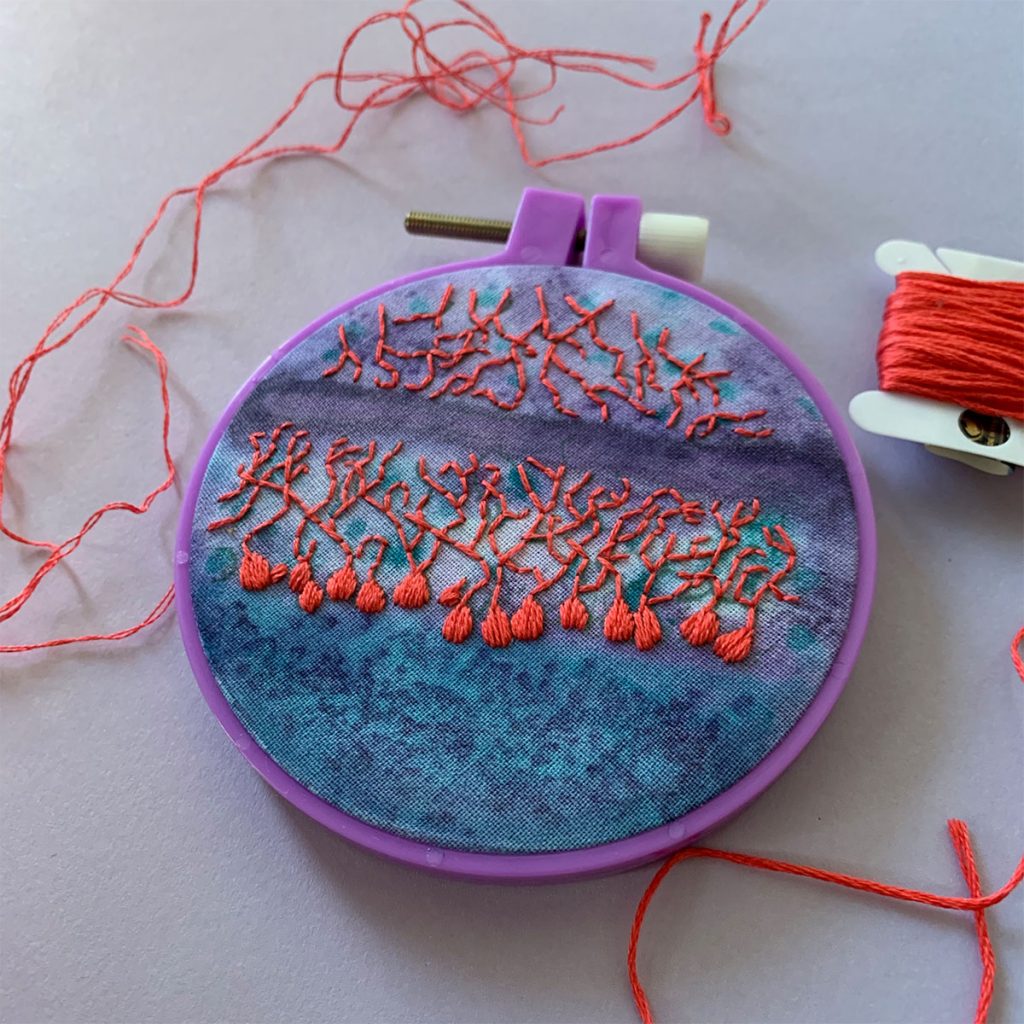 Neurons in the cerebellum stitched in bright pink with a purple and blue background. 