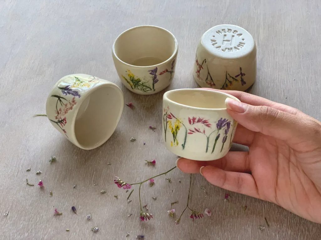 Four mall white cups without handles with painted imprints of flowers. 