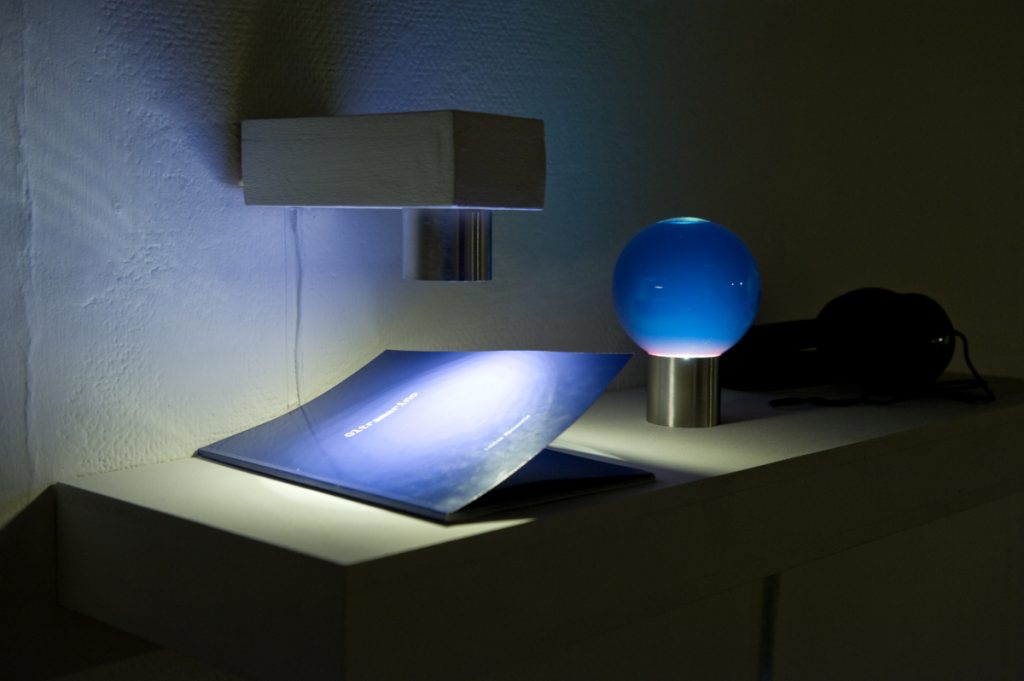 Shelf with a book and a blue glass orb. 