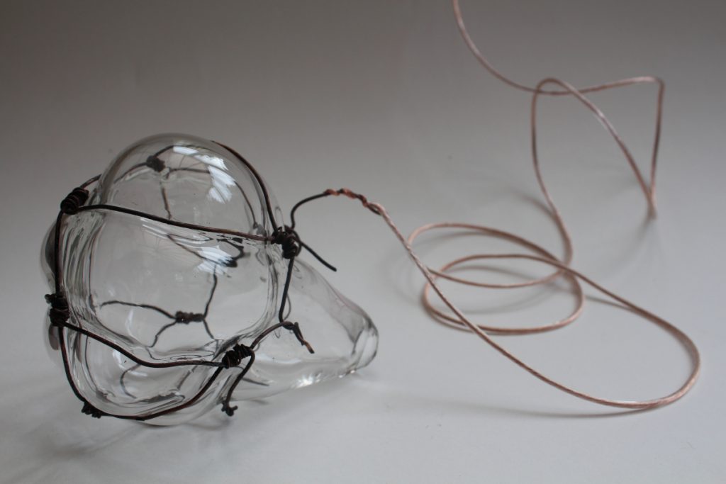 A blown glass container with large, bubble-like structures wrapped with thick metal wire