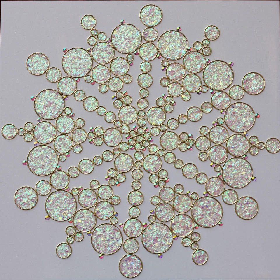 Iridescent pink and white circles of various sizes connected into a snowflake-like shape. 