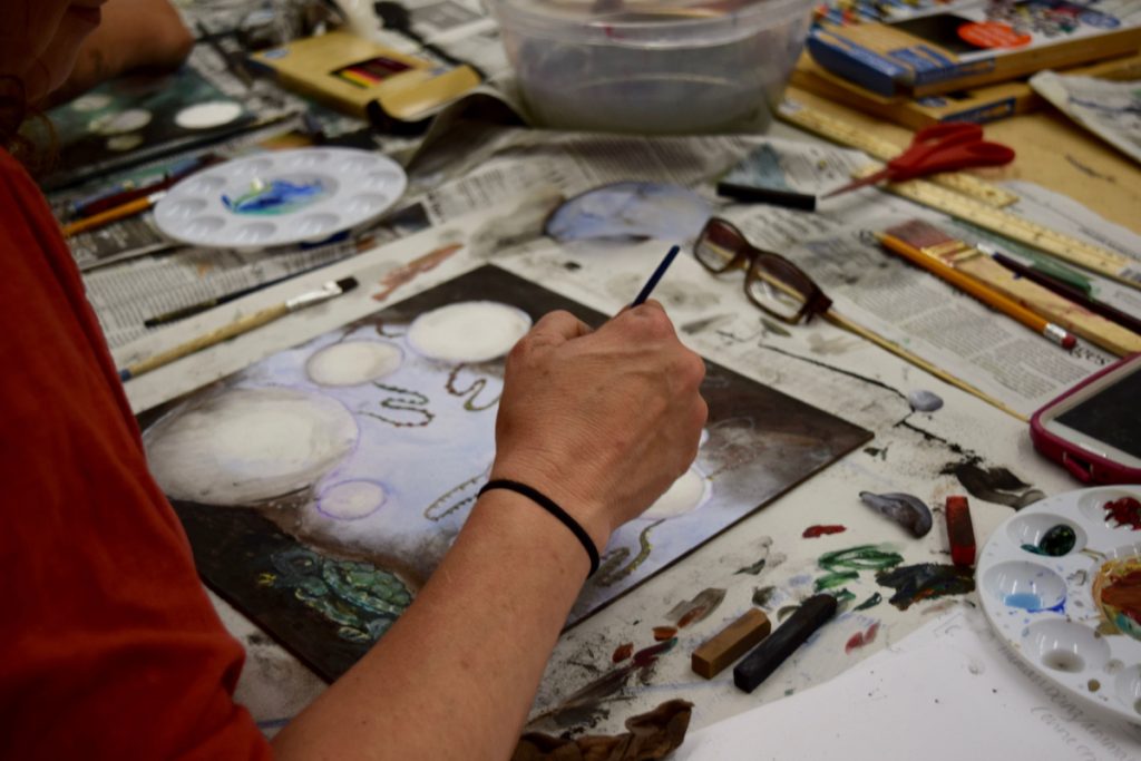 Image of a person's arm while painting at a workshop. 