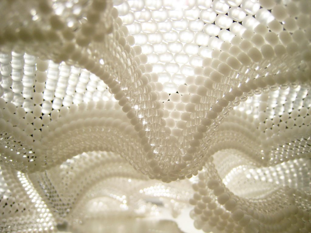 White spherical lamp made of joined beaded triangles. Image of interior surface. 
