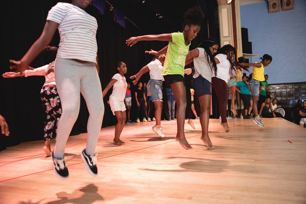 Girls practicing a dance and jumping on stage