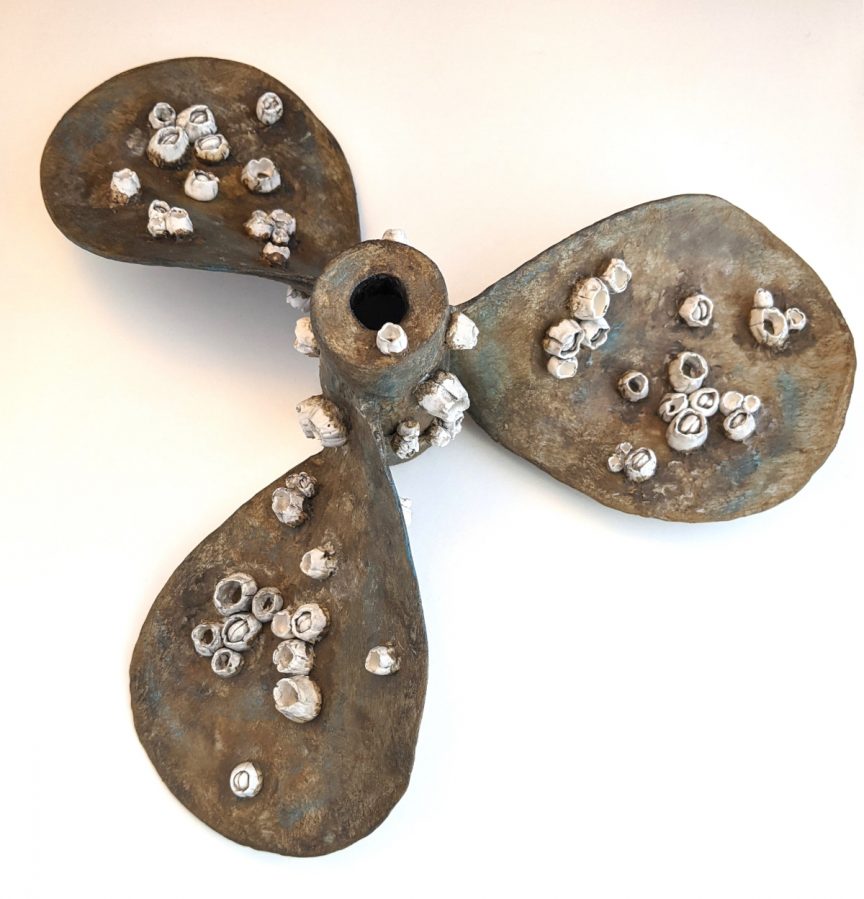 Rusted boat propeller with small barnacles growing on it