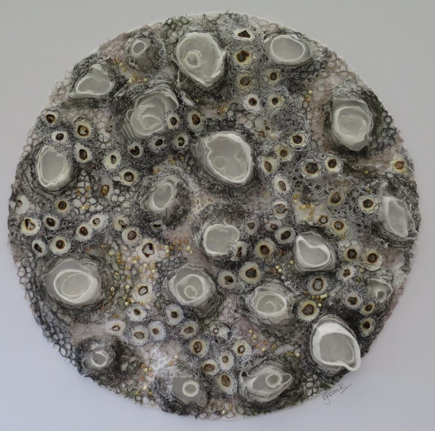Rounded piece with materials forming various circles all over, like barnacles are attached