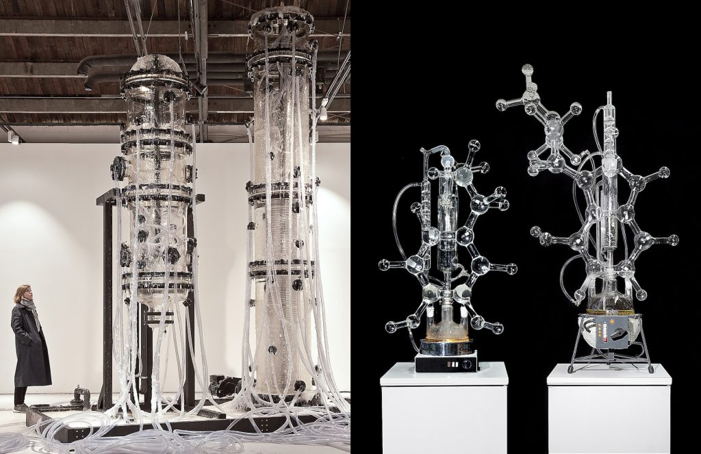 Left: A person looking up at very large stacked chemistry-like glassware, fitted with dangling plastic tubes. Right: Chemistry-like glassware in the shape of molecular structures sitting on white pedastals in front of a black background.